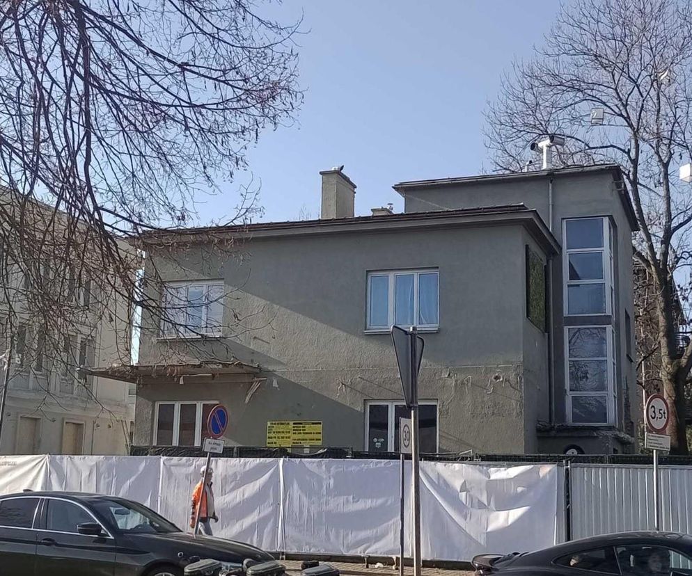 Modernistyczna willa przy al. Focha 24 w Krakowie, objęta rozbiórką bez zgody konserwatora zabytków, otoczona białym ogrodzeniem. Budynek posiada liczne ubytki w elewacji. O tym, jak deweloper rozbiera zabytkową willę bez zgody, przeczytasz na Architektura Murator Plus.