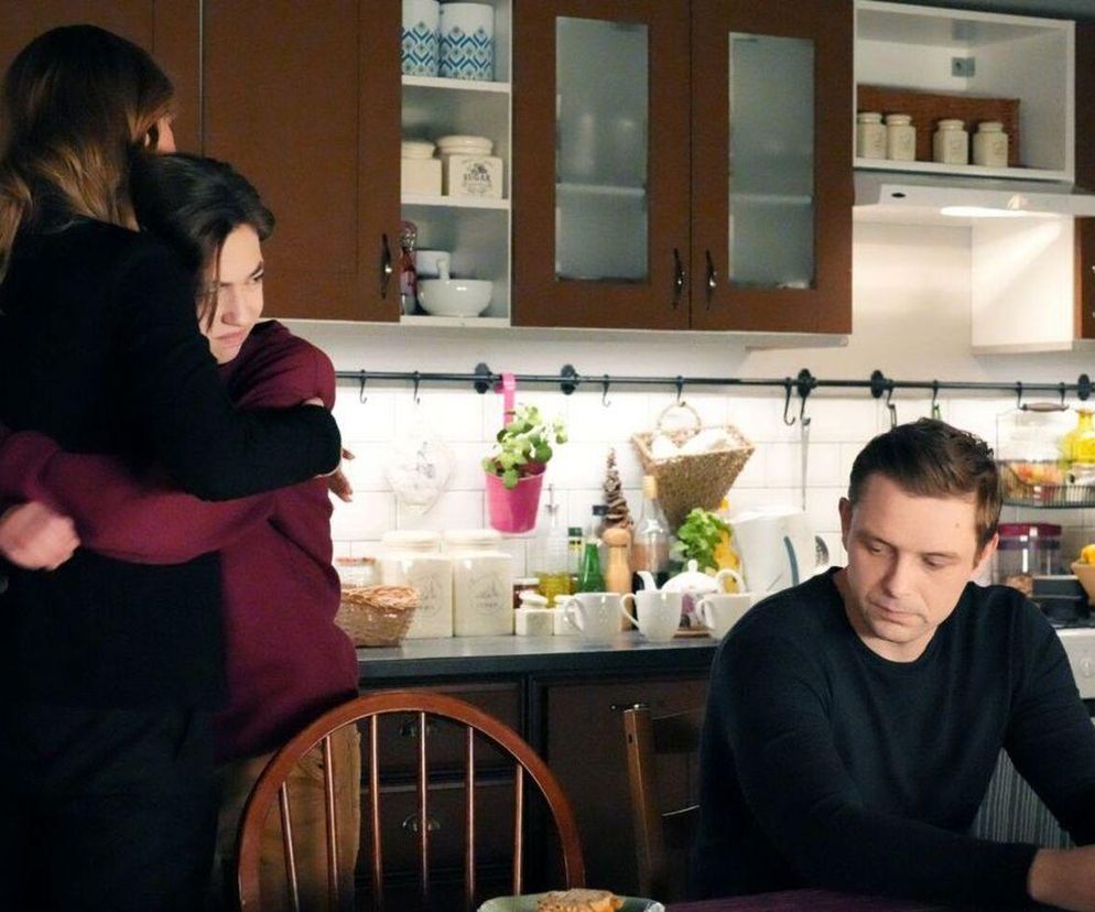 Asia (Anna Gzyra) pociesza Emila (Artem Malaszczuk) w kuchni, przytulając go. Z boku siedzi smutny Hubert (Marek Molak). Scena z serialu „Barwy szczęścia ukazuje emocjonalne chwile po powrocie Danka. Więcej o ich losach na Super Seriale.