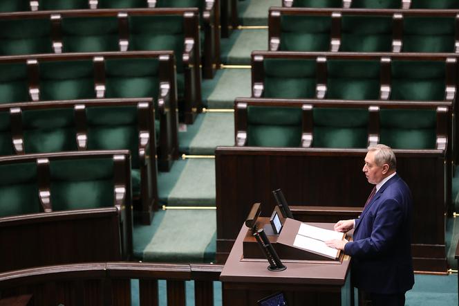 Przemawia minister infrastruktury Andrzej Adamczyk. W tle widać puste ławy sejmowe