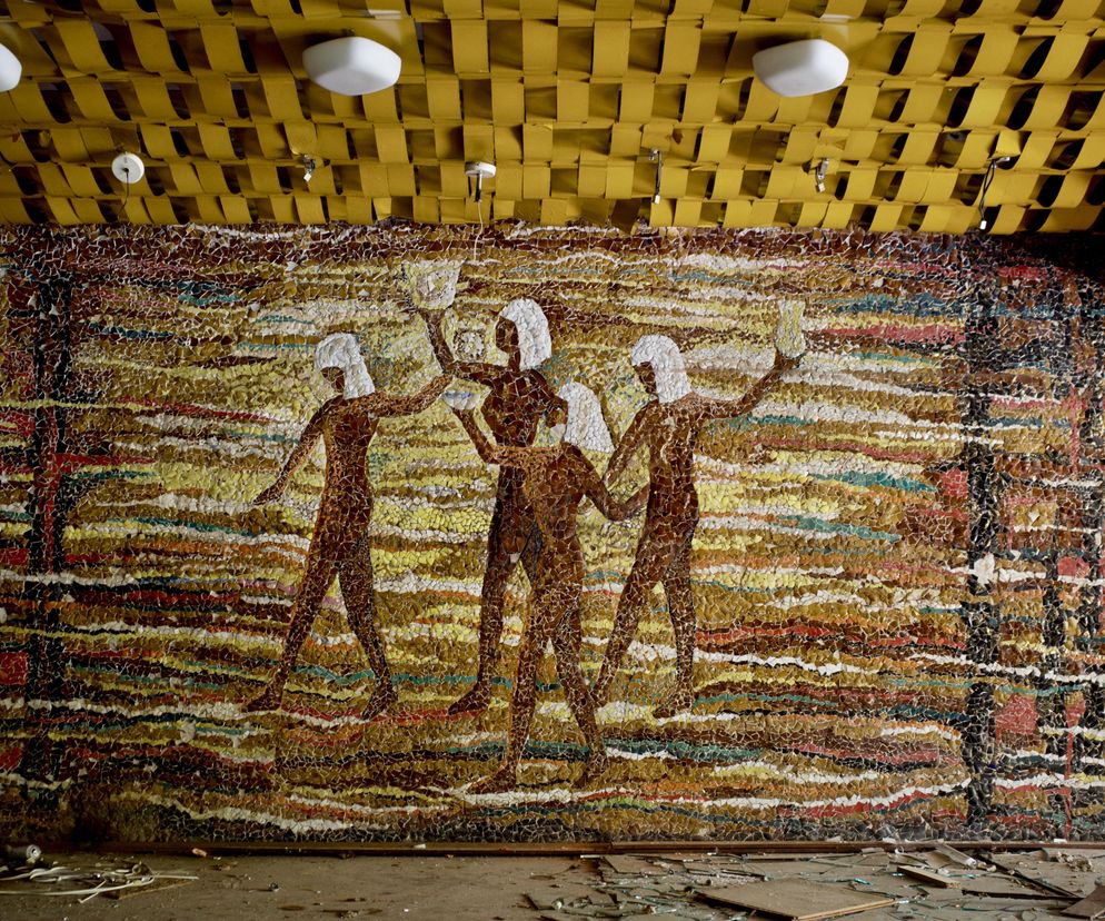 Mozaika Urszuli Okupniak i Janiny Jakubowskiej z 1972 roku przedstawiająca stylizowane postacie w egipskim krajobrazie na tle poziomych pasów. Fragmenty kolorowej ceramiki tworzą kompozycję na zdewastowanej ścianie ośrodka w Kiekrzu. Żółty, pleciony sufit i gruz na podłodze podkreślają stan opuszczenia. Więcej na Architektura Murator Plus.