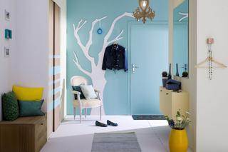 Niebieska ściana w przedpokoju z wieszakiem w kształcie drzewa