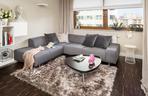 Szara sofa narożna w przytulnym salonie z kuchnią