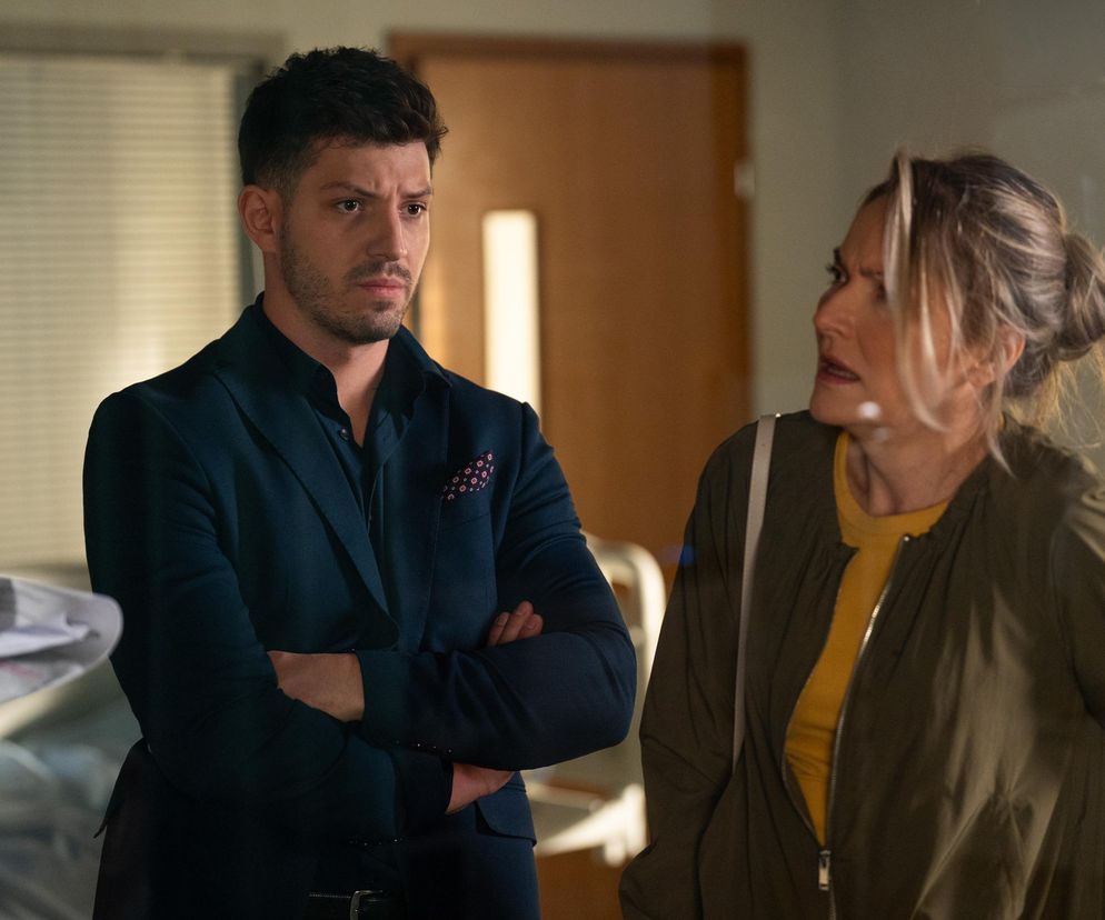 Aktor Jasper Sołtysiewicz jako Justin w ciemnym garniturze i jego matka Anna Bonna jako Zamilska w khaki kurtce w szpitalu. Troska Justina o chorą Olę i jego matkę w serialu Barwy szczęścia. Więcej o losach bohaterów przeczytasz na stronie Super Seriale.