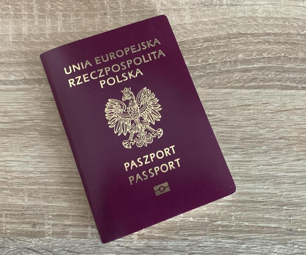 Paszport polski w kolorze bordowym leży na jasnym, drewnianym blacie. Na okładce widać godło Polski oraz napisy Unia Europejska, Rzeczpospolita Polska i Paszport. Zdjęcie symbolizuje nowe możliwości złożenia wniosku o paszport dla dziecka online, o czym przeczytasz na Super Biznes.
