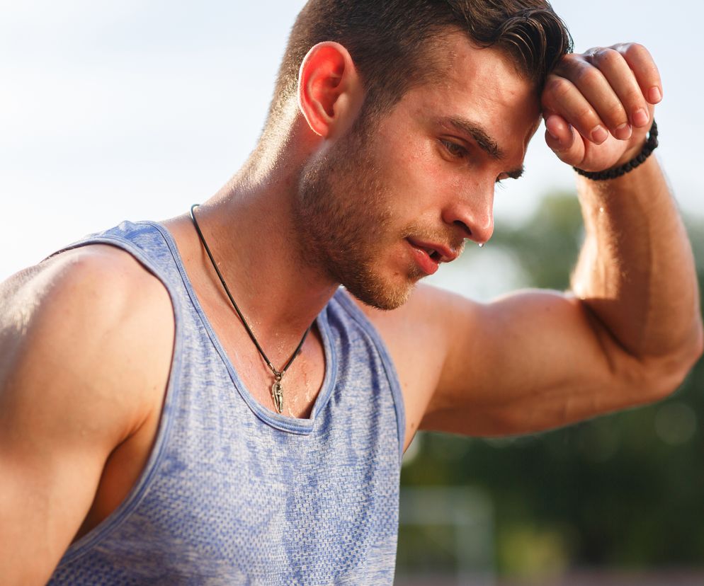 Wysportowany mężczyzna ocierający pot z czoła 