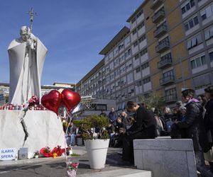 Świeczki, kartki z życzeniami, balony w kształcie serca, kwiaty składane są pod pomnikiem Jana Pawła II przed rzymską Polikliniką Gemelli