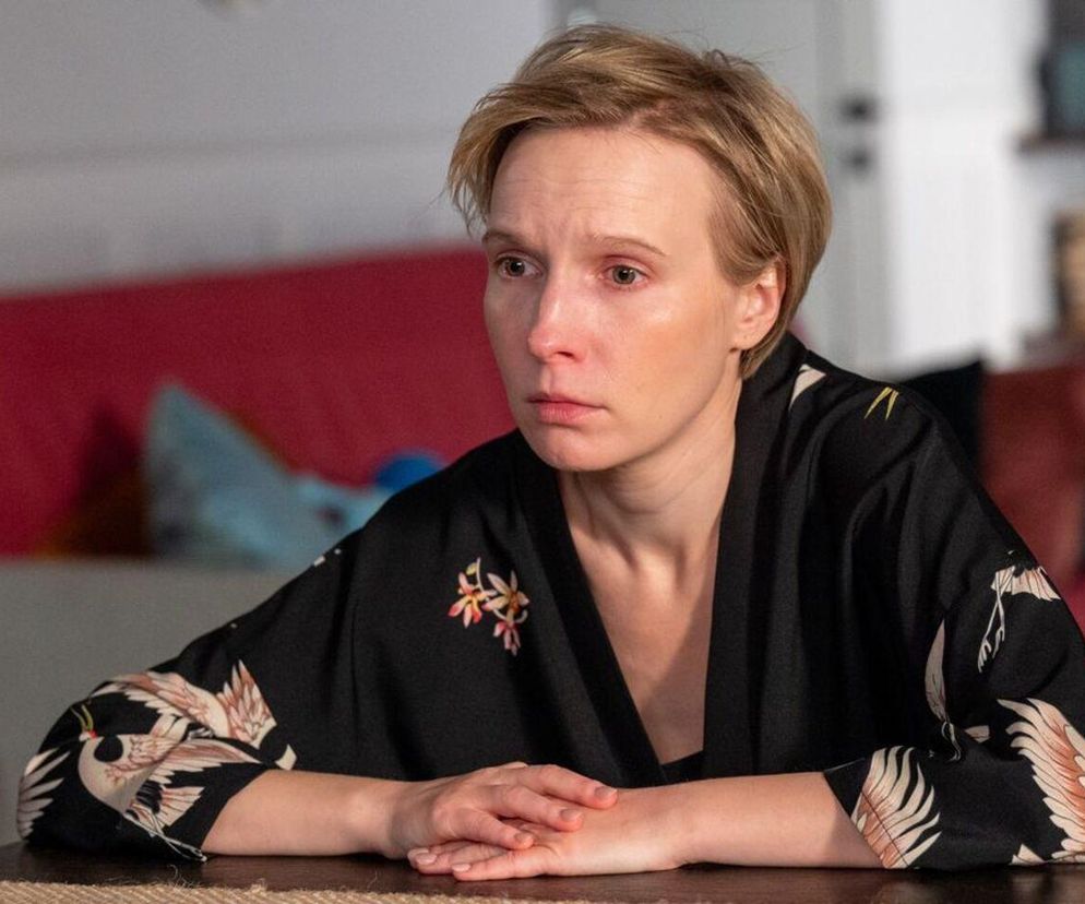 Aktor Weronika Nockowska jako Sonia z serialu Barwy szczęścia z poważnym wyrazem twarzy, zamyślona, w czarnym kimonie ze wzorami żurawi, siedząca przy stole. Dramatyczna historia Soni do przeczytania na Super Seriale.