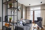 Ażurowy regał w stylu loft stanowi oryginalne przepierzenie pomiędzy kuchnią a salonem.