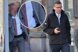 Morawiecki pod czujnym okiem ochrony na ulicach Warszawy. Spod marynarki wystaje broń