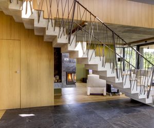 Prefabrykowane schody. Praktyczna rzeźba w centrum strefy dziennej – prefabrykowane schody ze stopniami wykończonymi 2-centymetrową warstwą drewna i artystyczną kutą balustradą