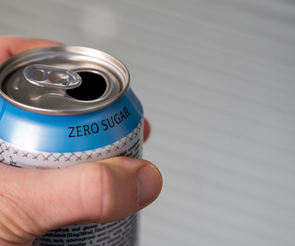 Dłoń trzymająca otwartą puszkę napoju typu zero sugar w kolorach niebieskim i srebrnym, z widocznym napisem ZERO SUGAR, symbolizuje zagrożenie dla wątroby i nerek. Więcej o wpływie słodzików na zdrowie przeczytasz na Poradnik Zdrowie.