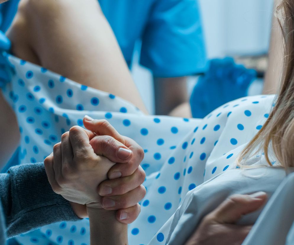 Kobieta na porodówce trzymana za rękę 