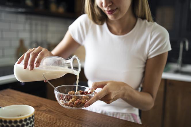 Kobieta nalewa mleko do miseczki z musli