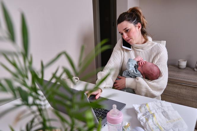matka z noworodkiem siedząca przed laptopem