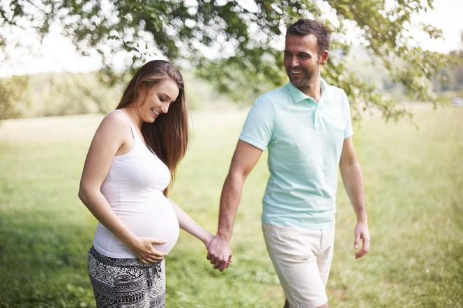 Kobieta w ciąży z mężczyzną na spacerze w parku