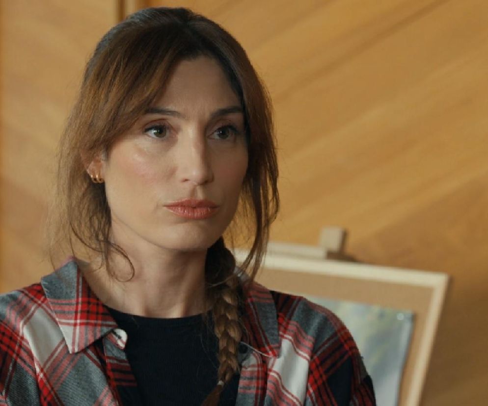 Aktorka Orina Krajewska jako Celina Brońska, w czerwono-białą kratę koszuli, wpatrzona z zadumą w dal. Scena z serialu „Barwy szczęścia”, gdzie Celina obwinia się za zniknięcie Łukasza. Więcej o losach bohaterów przeczytasz na portalu Super Seriale.