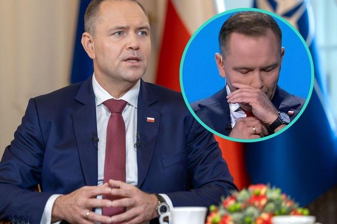 Prezydent Karol Nawrocki podczas wywiadu, ubrany w granatowy garnitur i bordowy krawat, z wpiętą polską flagą. Na pierwszym planie widać jego dłonie splecione na stole. W prawym górnym rogu okrągłe zdjęcie zrobione podczas uroczystości ONZ, gdzie zakładał woreczek nikotynowy pod wargę. O snusach i woreczkach nikotynowych przeczytasz na Poradnik Zdrowie.