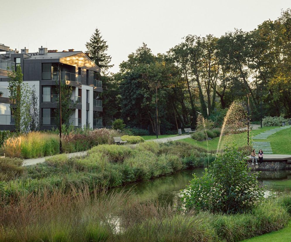 Zespół mieszkaniowy Opacka w Gdańsku z nowoczesnymi budynkami z balkonami i dużymi przeszkleniami, otoczony zielenią parku miejskiego z malowniczym stawem i ścieżkami spacerowymi, gdzie można odpoczywać, co prezentuje Architektura Murator Plus.