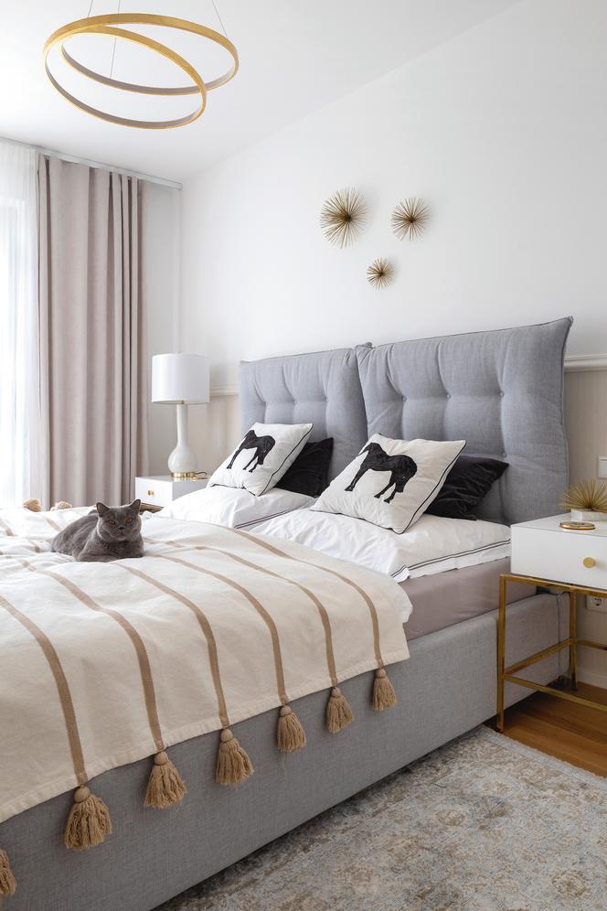 Sypialnia z szarym tapicerownym łóżkiem