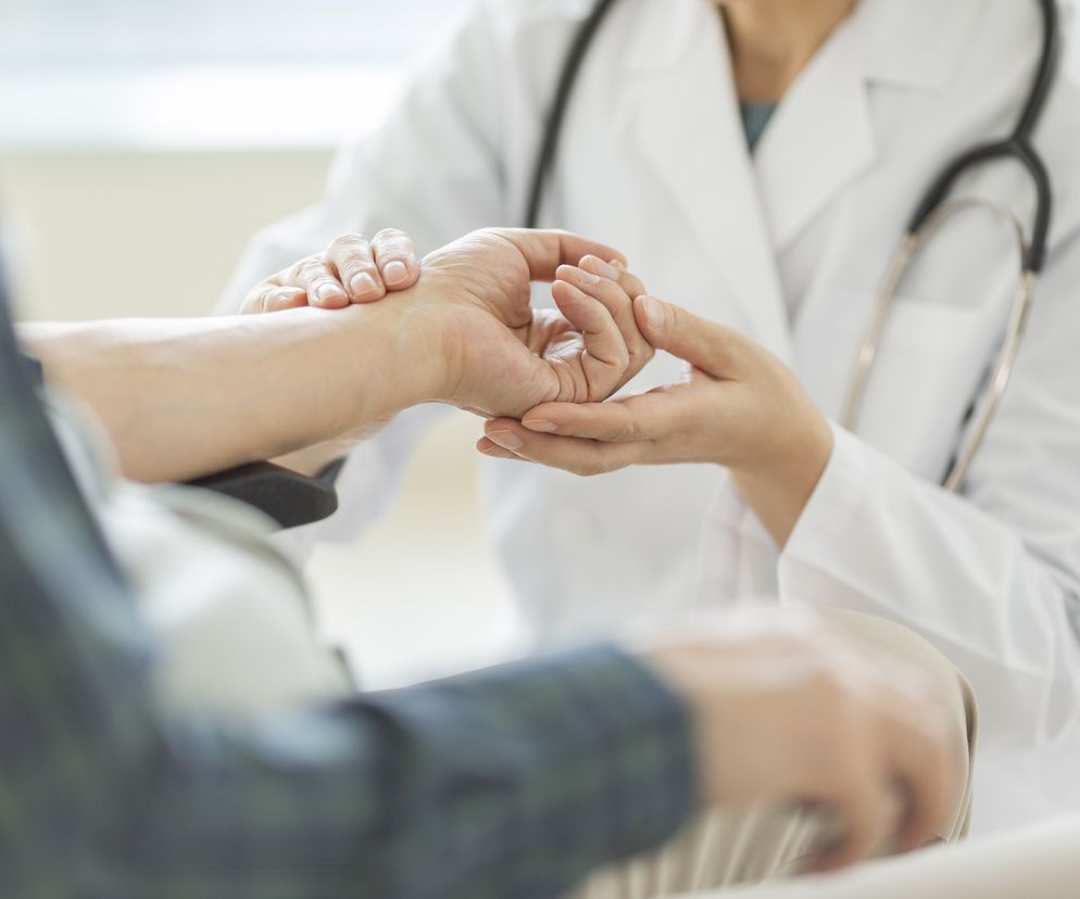 Lekary ujął pacjenta za rękę tuż nad przegubem. 