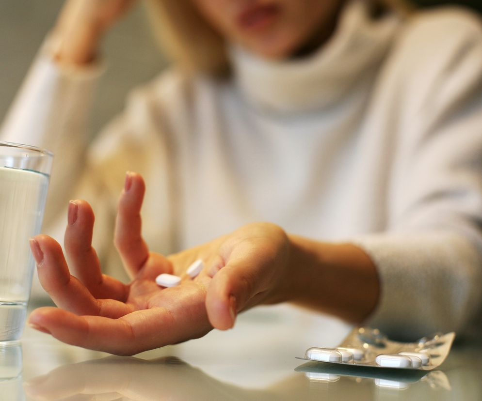 Młoda kobieta trzyma tabletki w ręce.