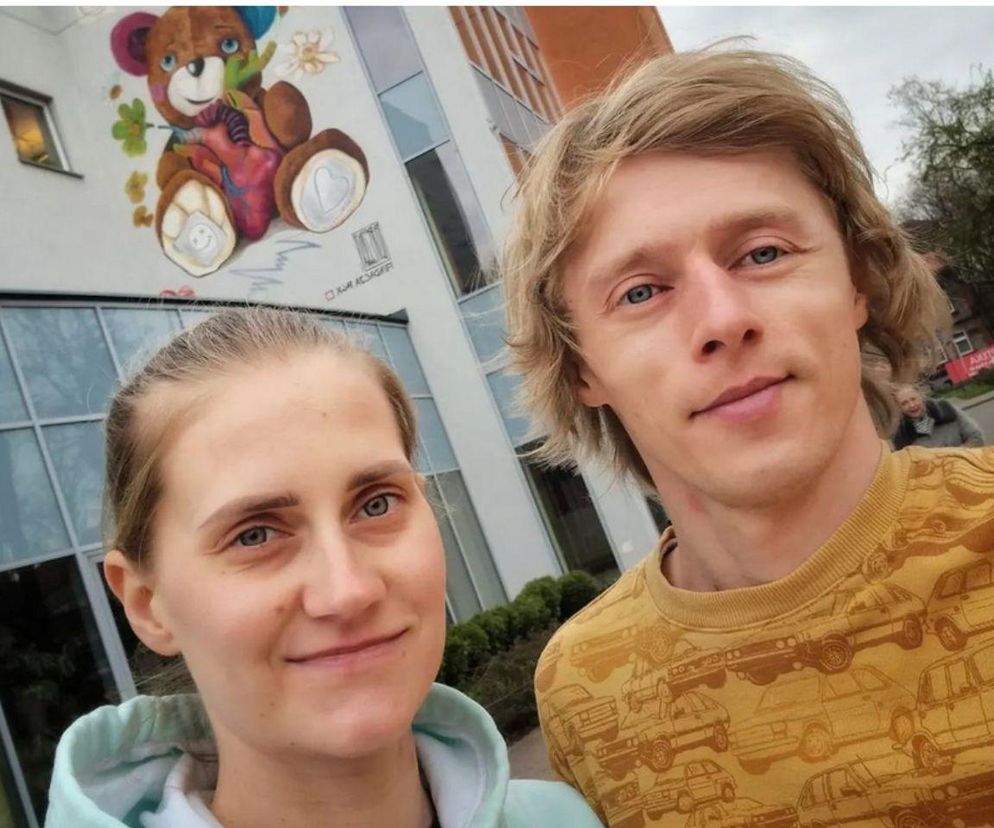 Uśmiechnięci Dawid i Marta Kubaccy na tle budynku. O narodzinach ich syna przeczytasz na SE.