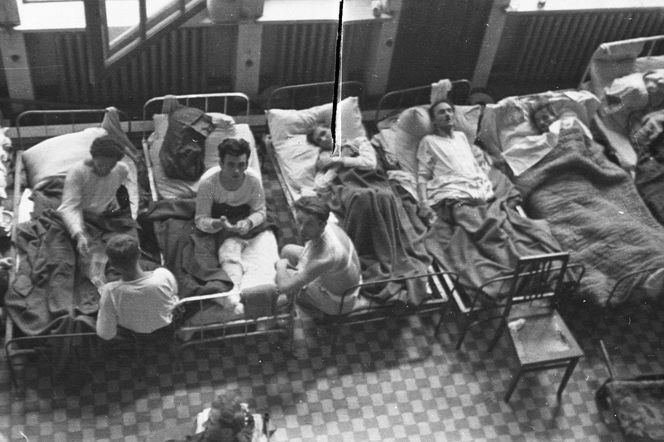 Fotografia z Powstania Warszawskiego. Ranni leżący na korytarzu powstańczego szpitala, w budynku Powszechnego Banku Związkowego przy ul. Zgoda 11.