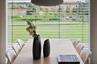 Stół jadalniany przy oknie z widokiem na ogród w nowoczesnymn domu