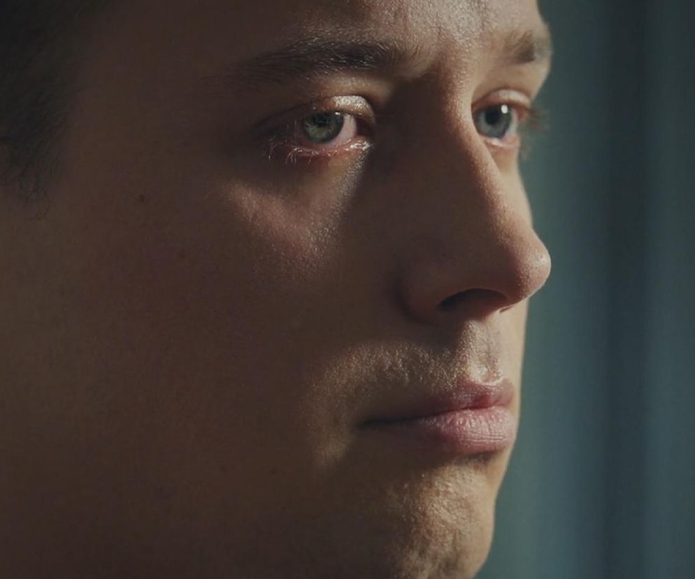 Zbliżenie na twarz Dominika Walata, granego przez Bartosza Surówkę, z serialu M jak miłość. Młody mężczyzna ma zamyślony, wręcz przejęty wyraz twarzy, z widocznymi emocjami w oczach, co nawiązuje do jego przyznania się do spowodowania wypadku Franki i Pawła w 1878 odcinku. Więcej o dramatycznych wydarzeniach przeczytasz na Super Seriale.