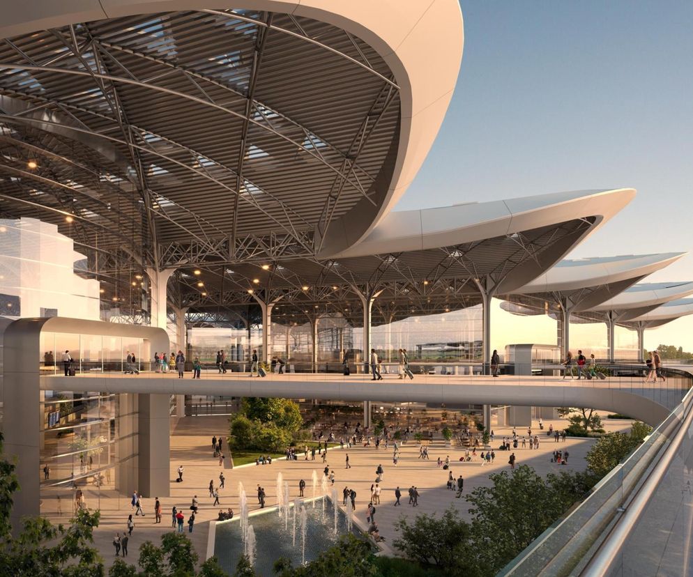 Wizualizacja nowoczesnego dworca kolejowego lub lotniska CPK z przeszklonymi fasadami, rozległym placem z fontanną i licznymi ludźmi, spacerującymi po terenie. Projekt architektoniczny imponuje rozłożystym dachem i kładkami dla pieszych, o planach inwestycyjnych przeczytasz na Super Biznes.