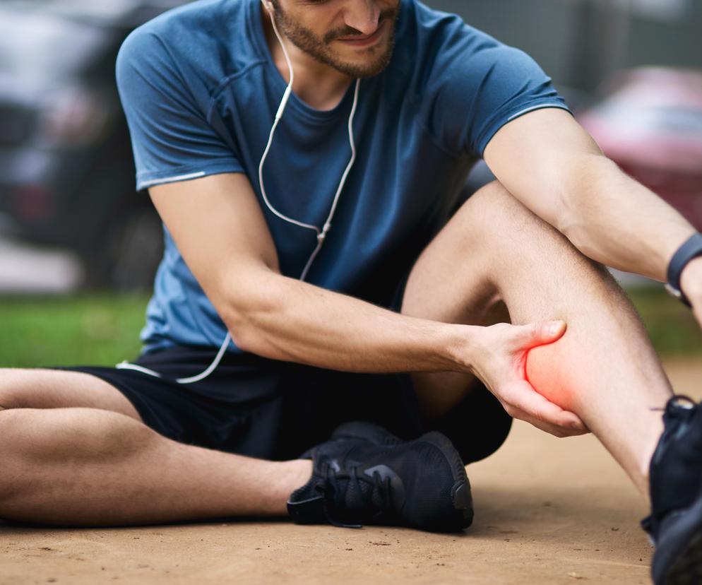 Mężczyzna trzymający się za łydkę 