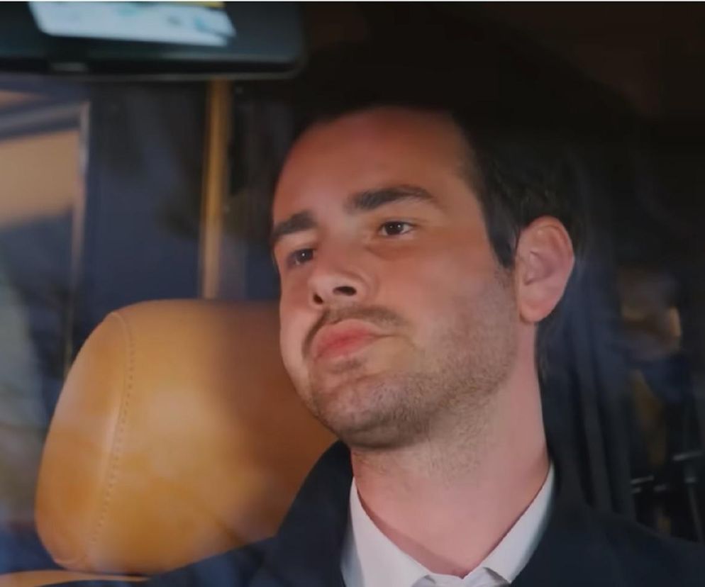 Młody mężczyzna, Levent, o ciemnych włosach i lekkim zaroście, z zaciętą miną w samochodzie, ubrany w ciemną marynarkę i białą koszulę. Jest to kluczowy moment z serialu „Miłość i Nadzieja”, gdzie Levent planuje zabójstwo. Więcej szczegółów na temat tej intrygującej historii znajdziesz na Super Seriale.