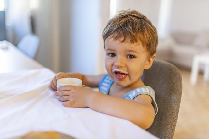 mały chłopiec pijący mleko z kubeczka