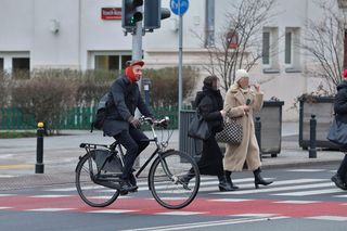 Maciej Gdula na rowerze. Chroni uszy przed chłodem