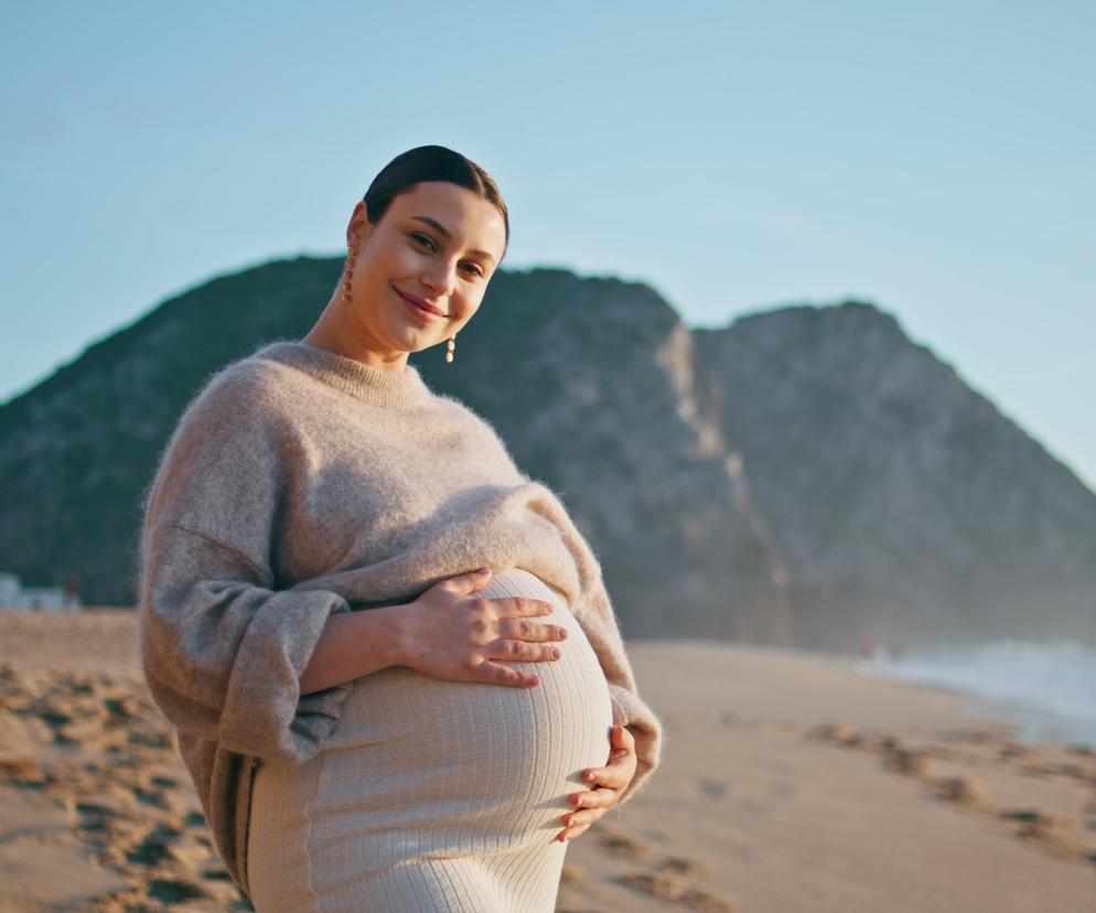 Kobieta w ciąży na plaży. Jaki jest najlepszy wiek na ciążę?