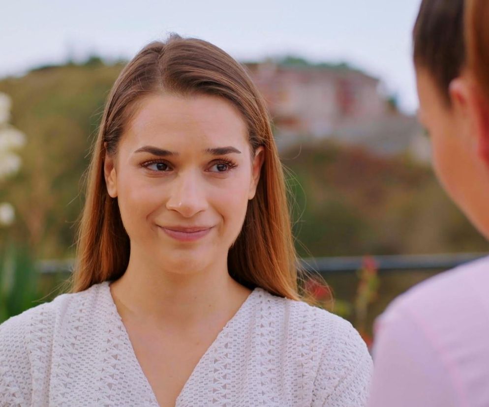 Yildiz uśmiechnięta spogląda na drugą osobę z bliska. Ma długie, brązowe włosy i ubrana jest w białą, dzianinową bluzkę. W tle zamazany krajobraz. Postać pochodzi z serialu Miłość i nadzieja. Więcej o tym na Super Seriale.