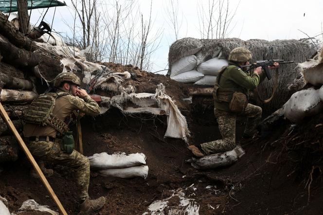 Żołnierze ukraińscy strzelają z karabinów szturmowych w okopie na linii frontu z wojskami rosyjskimi w obwodzie ługańskim