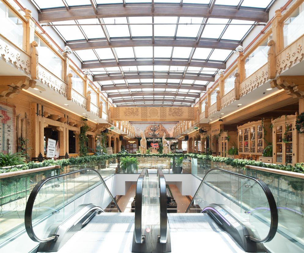 Wnętrze galerii na Krupówkach z drewnianymi zdobieniami i przeszklonym dachem. O architekturze Zakopanego czytaj w Architektura.