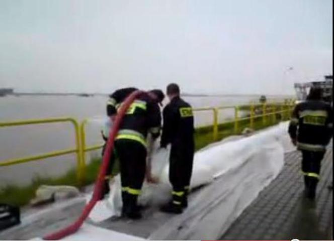 Powódź w Tczewie. Strażacy układają rękaw przeciwopowodziowy 
