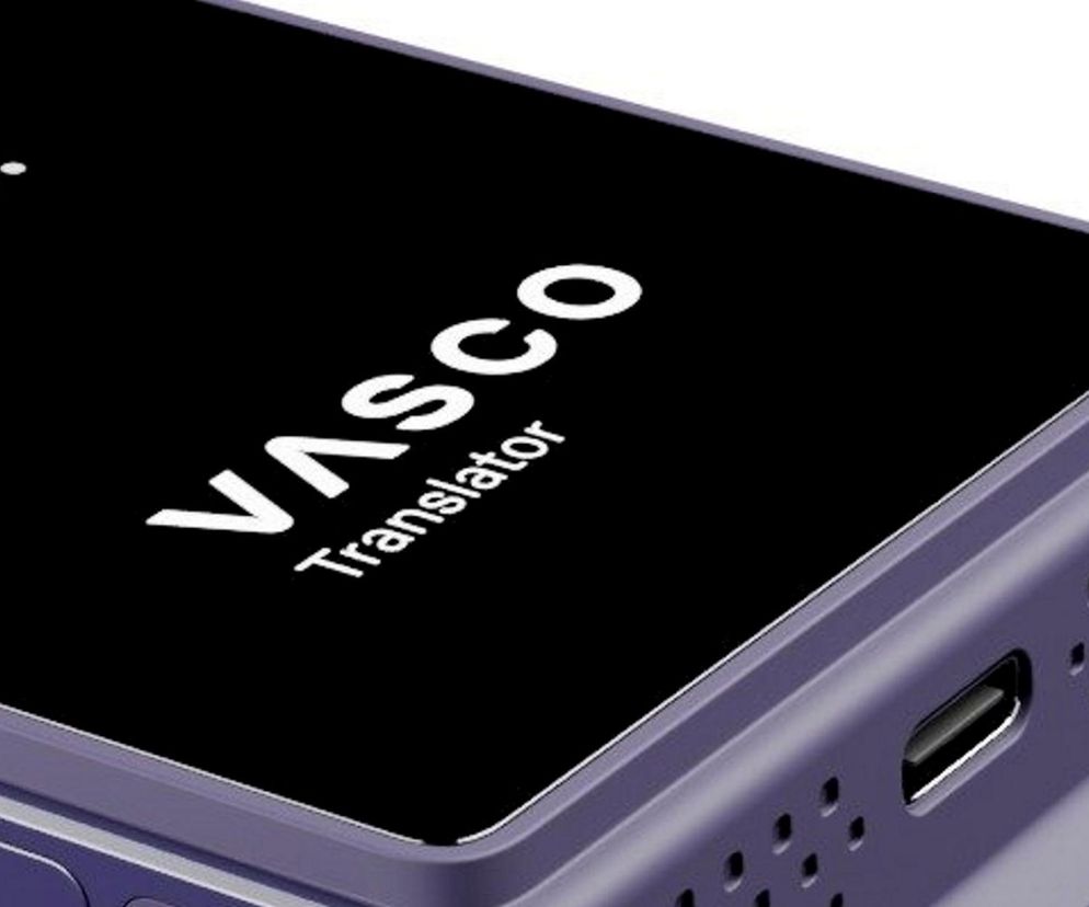 Fioletowe urządzenie Vasco Translator V4 z czarnym ekranem i widocznym napisem Vasco Translator oraz fragmentem słowa ¡Hola!. Obok ekranu widoczne głośniki i port USB-C. Więcej o tym, jak ten polski produkt podbija świat, przeczytasz na Super Biznes.