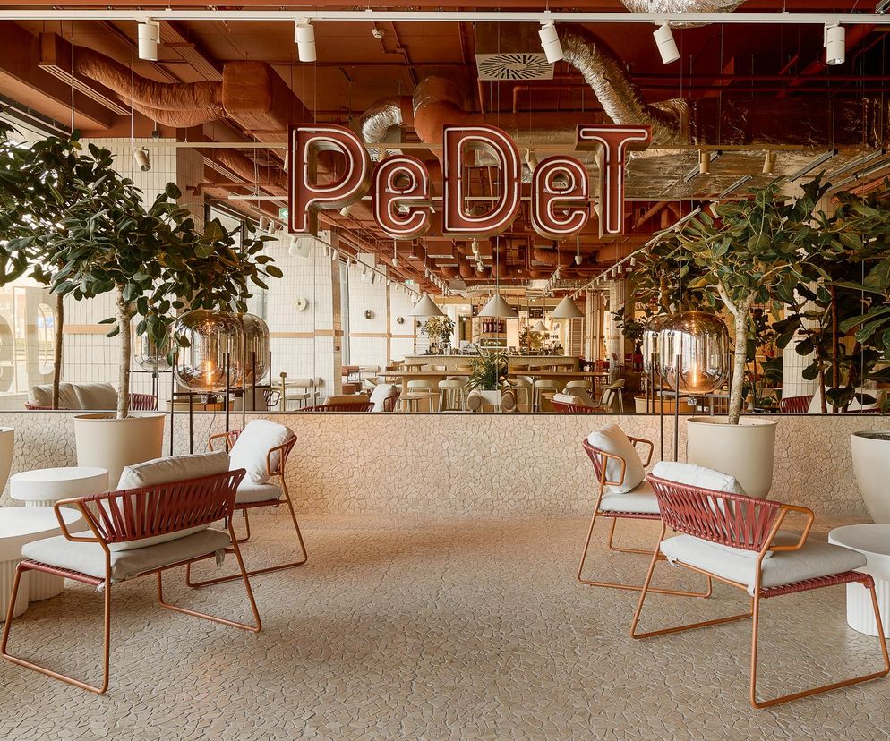 Wnętrze PEDET Strefa Food Hall w Domu Handlowym Renoma we Wrocławiu, z charakterystycznym neonem PeDet, donicami z roślinnością, jasnymi meblami w części lounge oraz terakotową posadzką. To zgłoszenie do konkursu Życie w Architekturze, o którym przeczytasz więcej na Architektura Murator Plus.