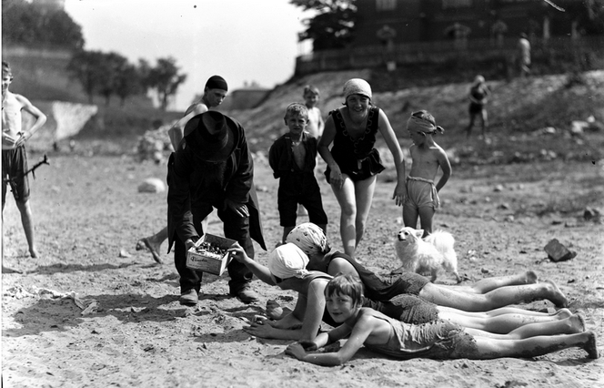 Plażowicze podczas wypoczynku. Widoczny sprzedawca obwarzanków, Kraków wrzesień 1929. Plaża nad Wisłą.