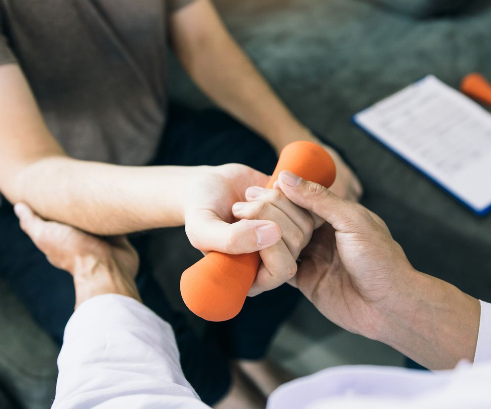 fizjoterapeuta pomaga pacjentom podnosić hantle podczas rehabilitacji
