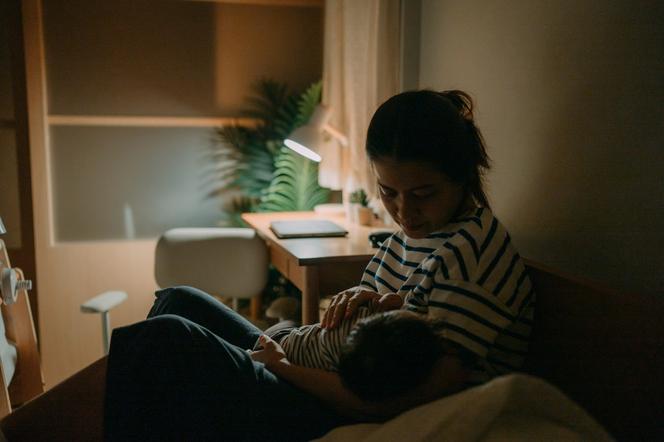 mama karmiąca piersią niemowlę w nocy przy zapalonej lampce
