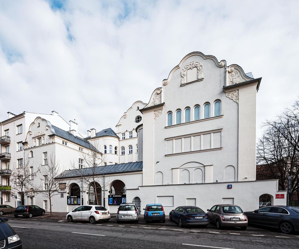 Zrewitalizowany Teatr Baj przy ul. Jagiellońskiej 28 w Warszawie, biała fasada z ozdobnymi detalami, a przed nim ulica z zaparkowanymi samochodami. Projekt FS&P Arcus, który prezentowany jest w Architekturze Murator Plus.