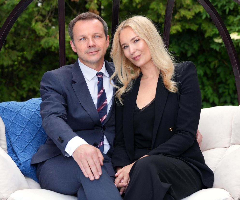 Aktorzy Marta Dąbrowska jako Karolina i Lesław Żurek jako Bruno z serialu Barwy szczęścia siedzący na bujanym fotelu ogrodowym. Marta Dąbrowska ma długie blond włosy, czarną marynarkę i bluzkę, a Lesław Żurek ciemny garnitur z krawatem. Zdjęcie ilustruje zmiany w hotelu Stańskich, o których przeczytasz na Super Seriale.