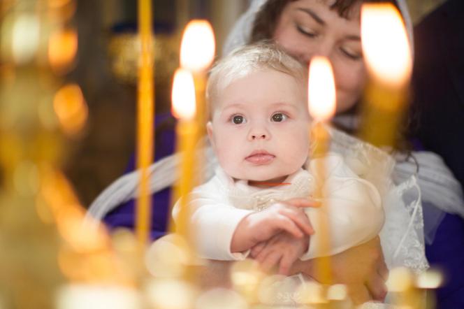 Chrzczone niemowlę w kościele na tle świec
