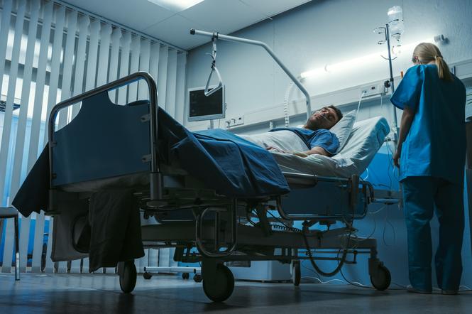 Mężczyzna w stanie ciężkim leżący w łóżku szpitalnym 