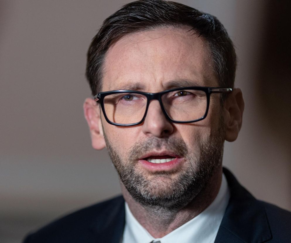 Zbliżenie na Daniela Obajtka, byłego prezesa Orlenu, w okularach i garniturze, z brodą, patrzącego w bok, z otwartymi ustami, co może symbolizować jego wypowiedź lub reakcję na zarzuty. Dowiedz się więcej o roszczeniach wobec niego na Super Biznes.