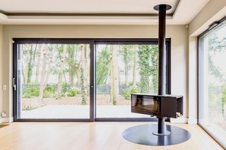 W tym domu jest przeszklone palenisko w formie prostopadłościanu na rurze. Jak futurystyczny kominek z lat 60.